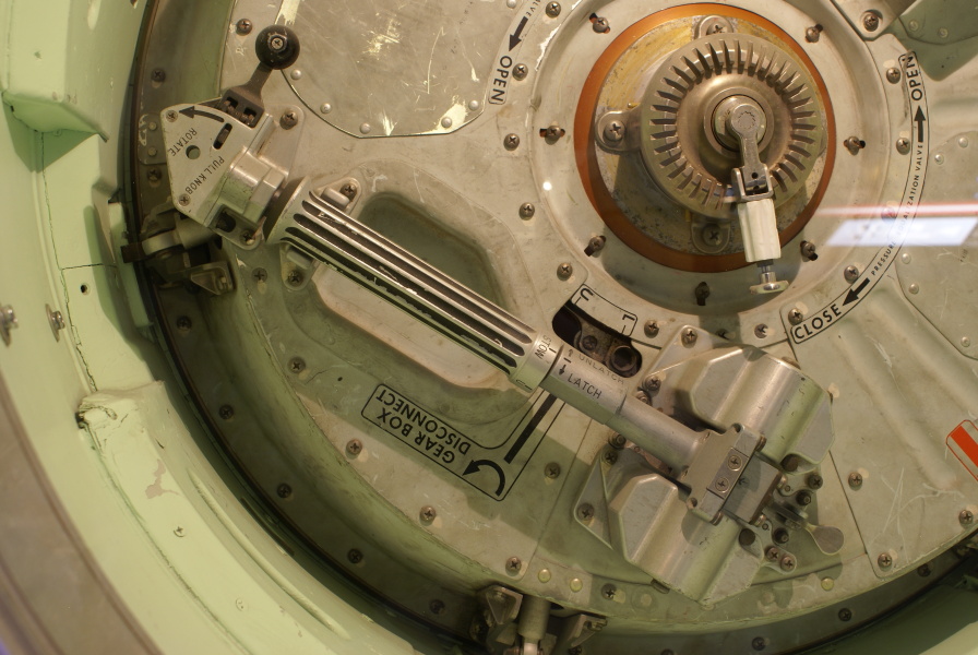 Latch actuator handle, drive mechanism, and gearbox on command module forward tunnel hatch in Apollo Probe & Drogue System at Kansas Cosmosphere.