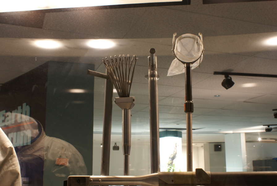 Soil sampler, adjustable scoop, tongs, and extension handle in the Lunar Hand Tool Carrier at Houston Museum of Natural Science