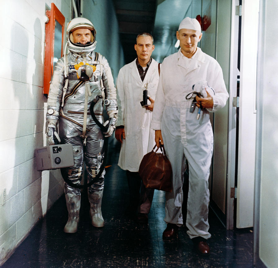 John Glenn in his Project Mercury space suit holding a portable ventilator